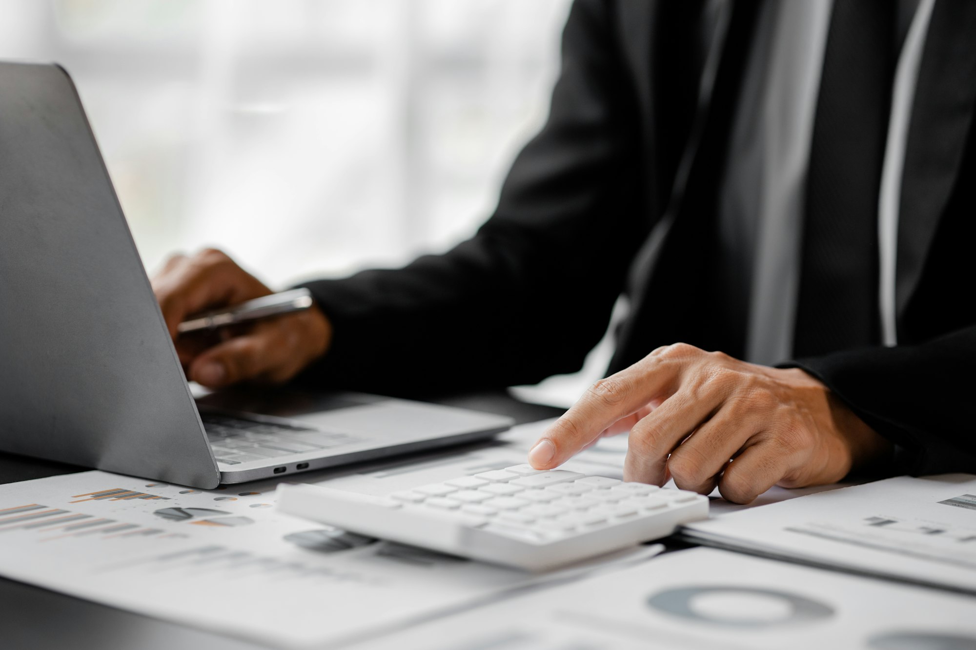 Businessman is using a calculator to calculate company financial figures from earnings papers.